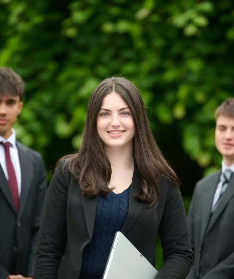 The Grange School Sixth Form Pupil standing outside with laptop.