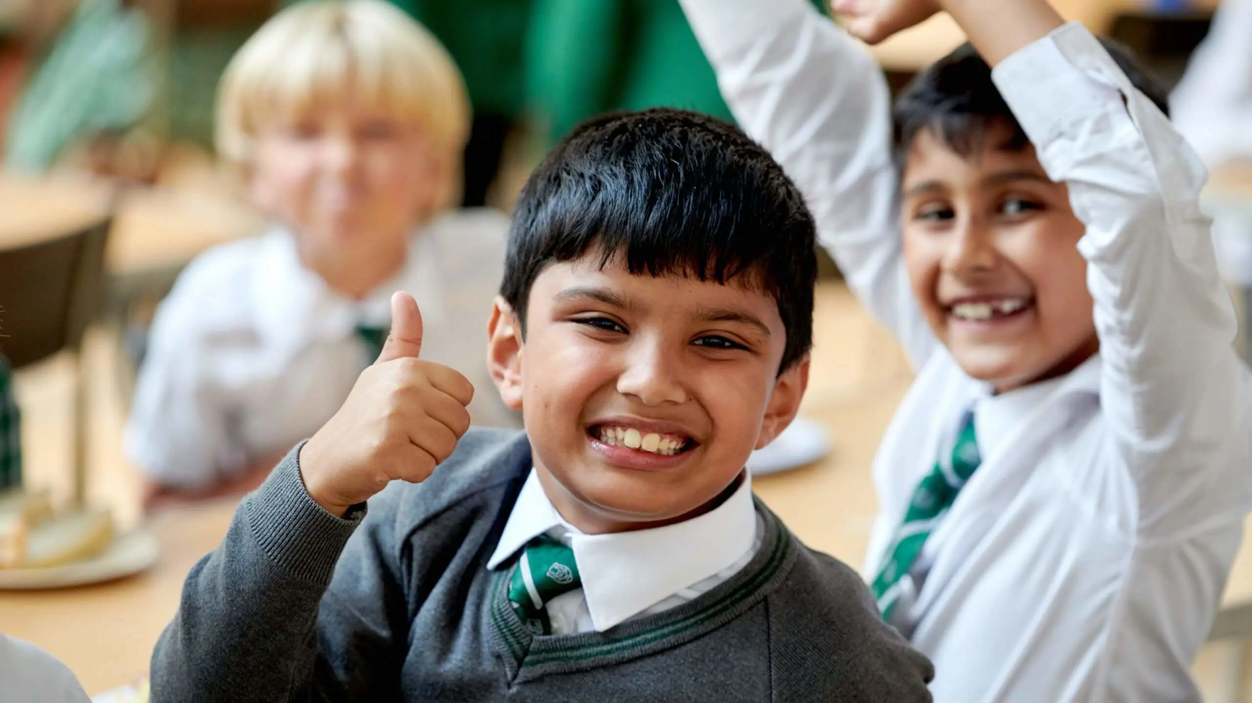 The Grange School Junior pupil thumbs up, smiling at lunch time.