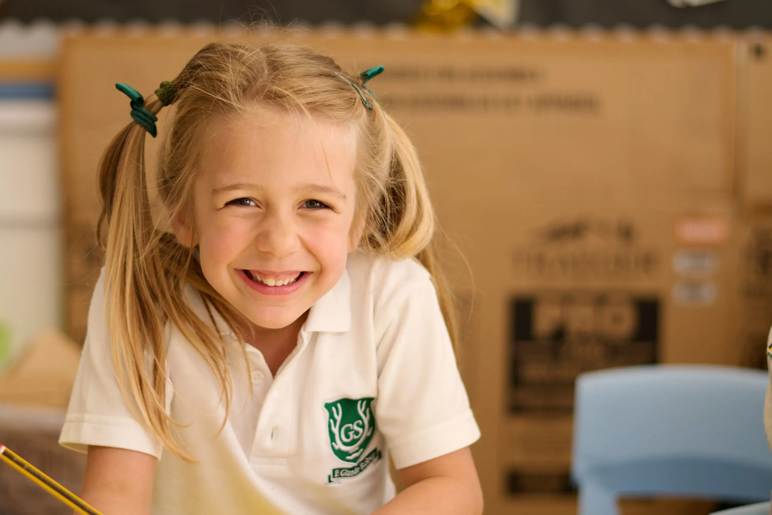 The Grange School Junior pupil smiling while completing work in a lesson.
