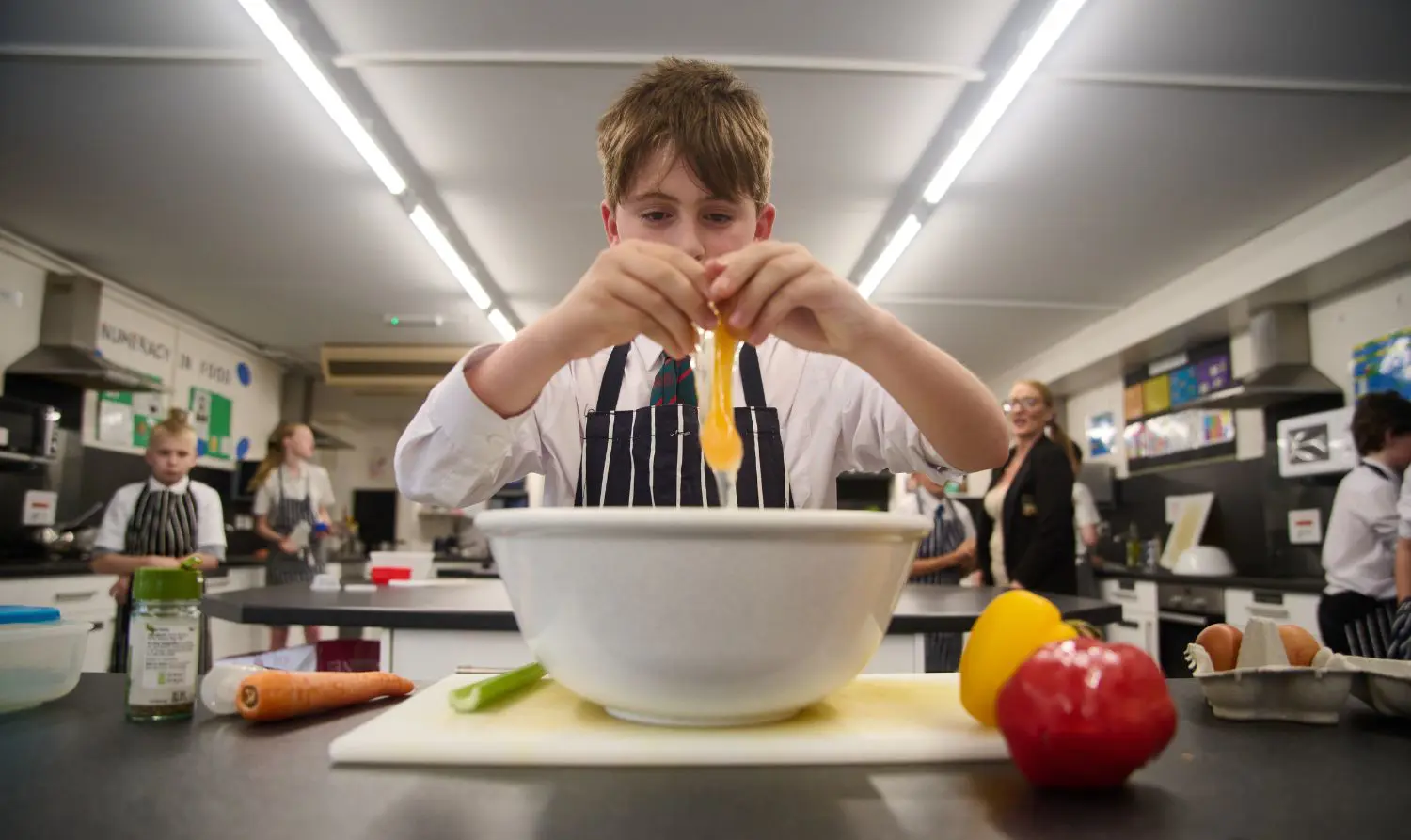 Senior pupil at The Grange School cracking an egg into a mixing bowl in a Food & Nutrition lesson.